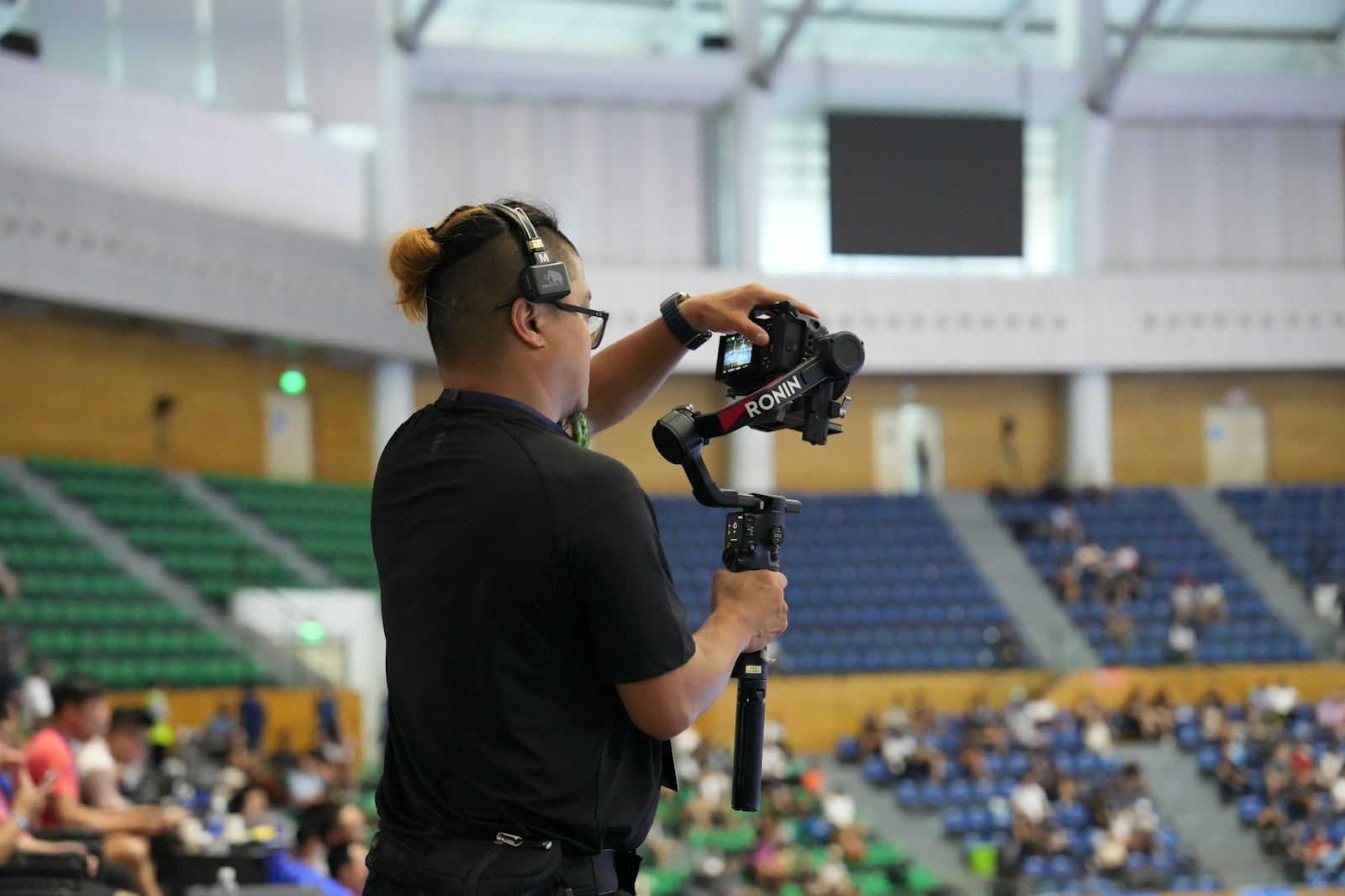 Camera operator filming an event with a camera mounted on a handheld gimbal stabilizer